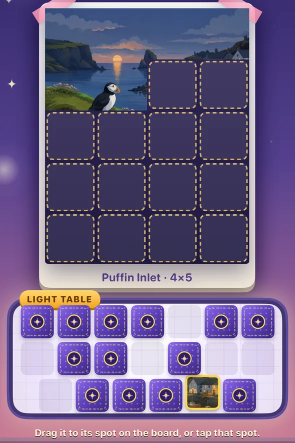 The board with a few tiles placed, and face-down tiles on the light table below it, one of them flipped